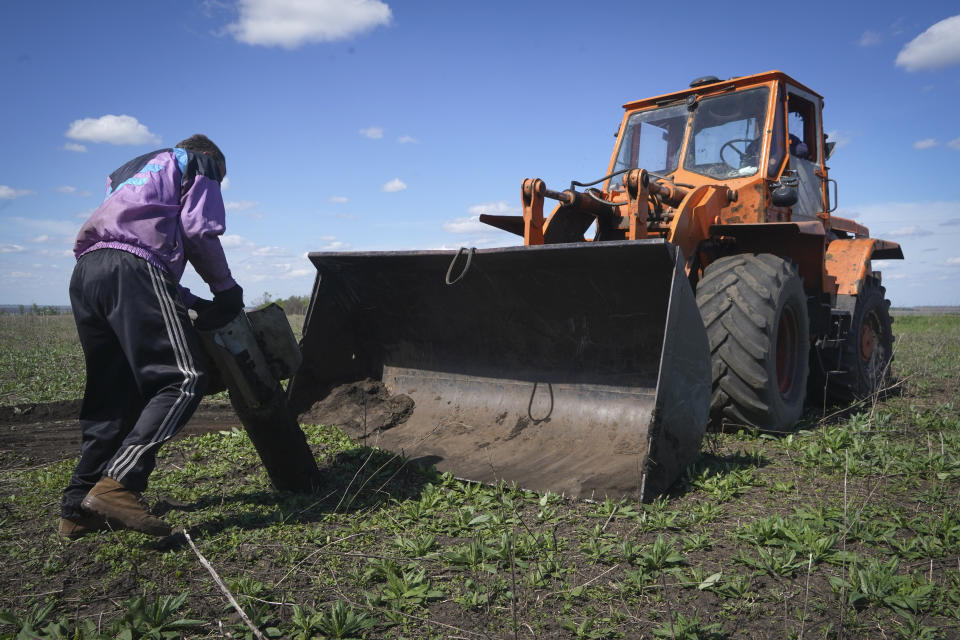 A farmer removes a fragment of a Russian missile as he works on his field in Izium, Kharkiv region, Ukraine, Saturday, April 20, 2024. (AP Photo/Andrii Marienko)