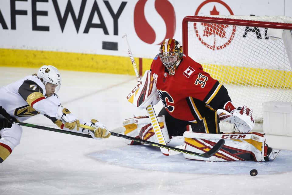 Vegas Golden Knights' William Karlsson, left, stretches to try and get the puck past Calgary Flames goalie David Rittich during the third period of an NHL hockey game in Calgary, Alberta, Sunday, March 8, 2020. (Jeff McIntosh/The Canadian Press via AP)