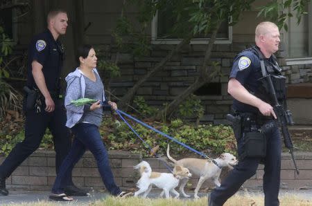 Police escort a woman and her dogs out of an apartment complex at the scene of a armed standoff with a man with a high powered rifle who is holding hostages in Chula Vista, California May 28, 2015. REUTERS/Sandy Huffaker