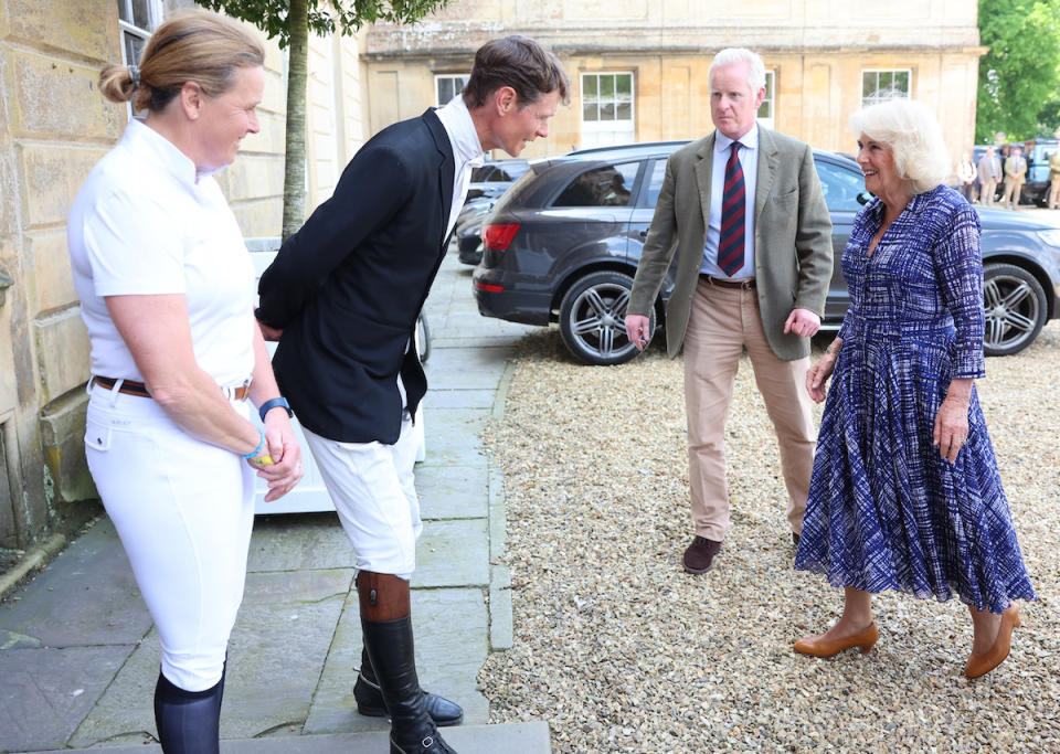 Queen Camilla in kitten heel shoes (R) is greeted by previous winners Pippa Funnell (L) and William Fox-Pitt (2nd L) as she arrives to attend the final day of the Badminton Horse Trials 2024 at Badminton House on May 12, 2024 in Badminton, Gloucestershire. 