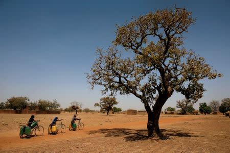 Girls carry water on their bicycles at a dispensary in Nedogo village near Ouagadougou, Burkina Faso February 16, 2018. REUTERS/Luc Gnago/Files