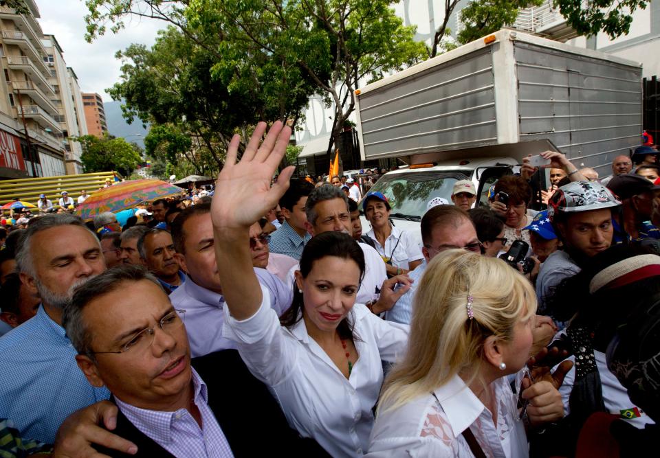 Maria Corina Machado, center, greets supporters upon her arrival to a rally in Caracas, Venezuela, Tuesday, April 1, 2014. Protesters wearing white T-shirts and hats in the red, yellow and blue, of Venezuela's flag have gathered to cheer the opposition lawmaker who was stripped of her seat in congress by the government last week. This is Machado's first major public appearance since Venezuela's Supreme Court confirmed the stripping of Machado's parliamentary seat after she addressed the Organization of American States at the invitation of Panama. (AP Photo/Fernando Llano)