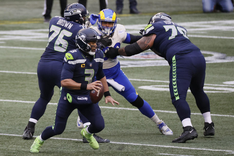 Russell Wilson of the Seattle Seahawks scrambles against defensive end Aaron Donald of the Los Angeles Rams during the NFC wild-card game on Jan. 09, 2021. (Steph Chambers/Getty Images)