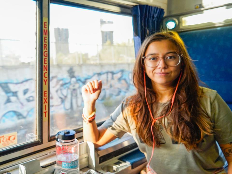 The author sits in a train car with graffiti out the window on the left