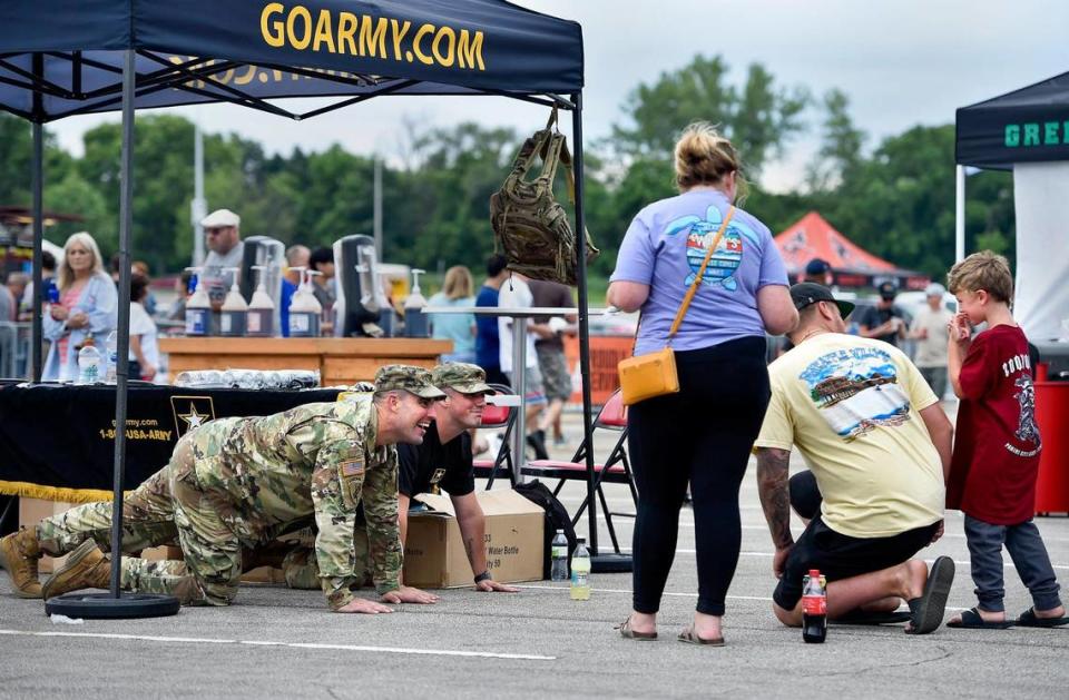 Staff Sgt. Kirby Karnes, left, and Spc. Travis Stevenson with the 418th Civil Affairs Battalion try to get 5-year-old Michael Brewer of Blue Springs to do a push up as Michael’s parents, Sabrena and Caleb Brewer, wait to see if Micheal will do it. The three-day Kansas City BBQ Festival in the parking lot of the GEHA Field at Arrowhead Stadium concluded Sunday, July 11, 2021.