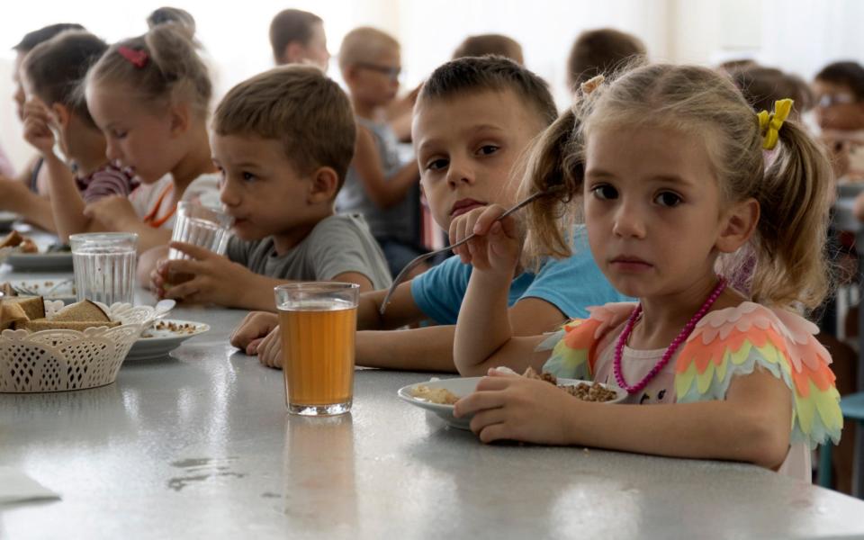 Children from an orphanage in the Donetsk region, eat a meal at a camp in Zolotaya Kosa on Friday, July 8 - AP