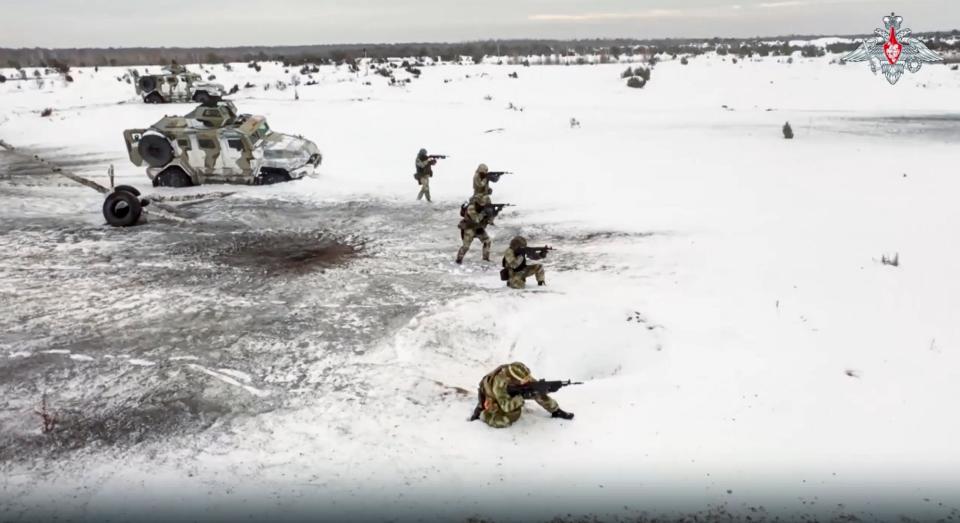 Russian servicemen stand ready to shoot in front of armored vehicles in the snow