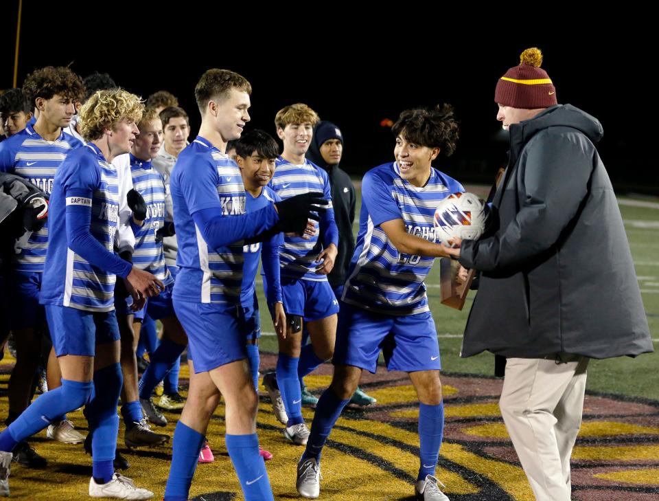 Mishawaka Marian senior Marco Aguilar receives the Clas 2A boys soccer semi-state championship trophy from Chesterton Athletic Director Jeff Hamstra following a 3-0 win over Leo Saturday, Oct. 21, 2023, at Chesterton High School.