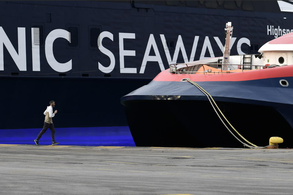 A man jogs during a 24-hour labour strike at the port of Piraeus, near Athens, Thursday, June 10, 2021. Greece's biggest labor unions stage a 24-hour strike to protest a draft labor bill being debated in parliament, which workers say will erode their rights. (AP Photo/Michael Varaklas)