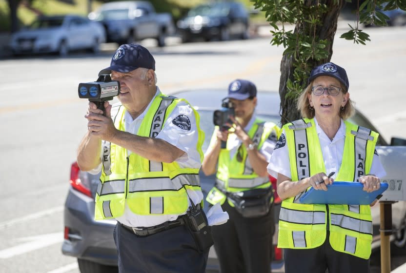 NORTHRIDGE, CA-JULY 24, 2019: left to right-Nishan Darakdjian, 73, and Karla Hanley, 68, use speed guns to catch motorists driving past the speed limit on Reseda Blvd. in Northridge as Amy Schneider, 63, writes down the speed they were going on July 25, 2019. They are volunteers with the Devonshire Community Police Station in Northridge. (Mel Melcon/Los Angeles Times)