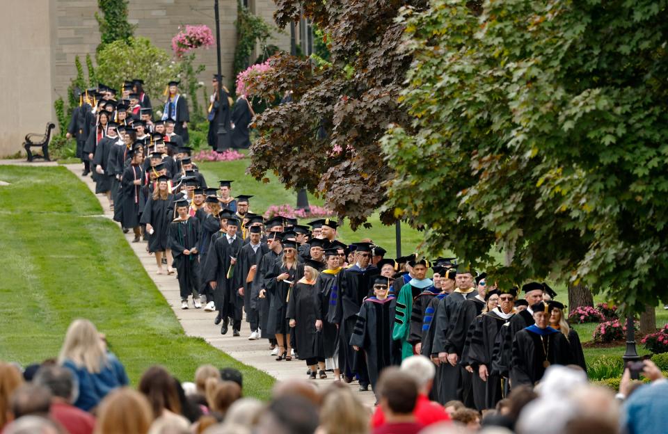 Led by Adrian College President Jeffrey Docking, the Adrian College Class of 2024, along with administration and staff, file onto the college' Mall Sunday during the spring commencement.