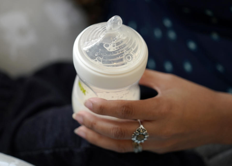 FILE - A woman holds a bottle of baby formula as she feeds her infant son in San Antonio on May 13, 2022. (AP Photo/Eric Gay, File)