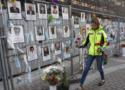 A woman puts flowers to portraits of St. Petersburg's medical workers who died from coronavirus infection during their work, hanging at an unofficial memorial in front of the local health department in St.Petersburg, Russia, Friday, Sept. 25, 2020. The number of daily new cases started to grow in late August in Russia, which has the fourth largest caseload in the world at 1.12 million infections. (AP Photo/Dmitri Lovetsky)