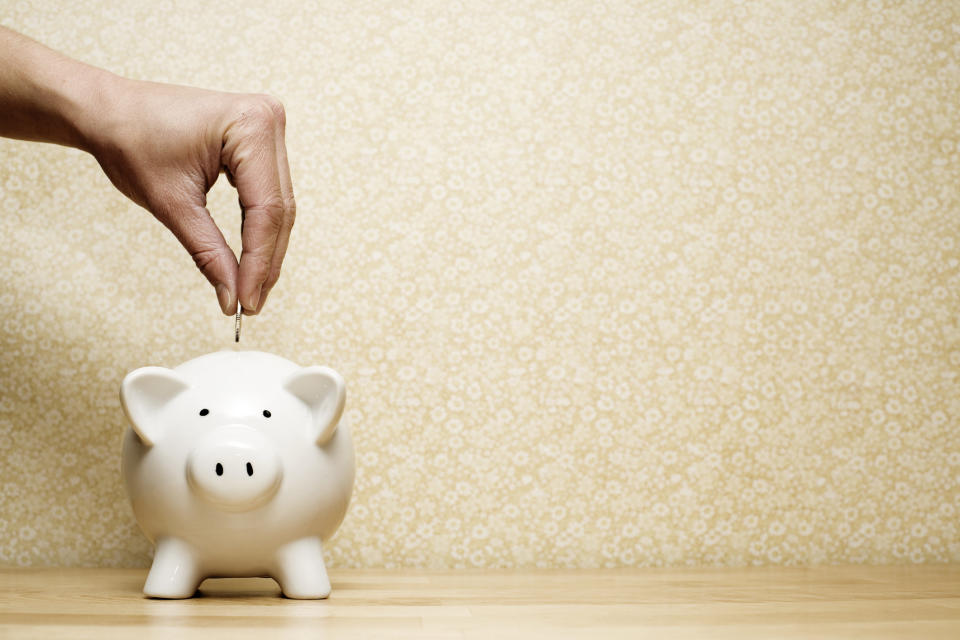 Hand putting coin into a piggy bank.