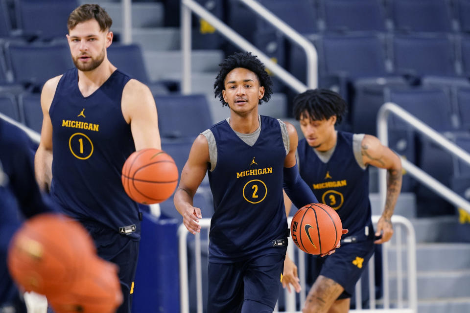 Michigan center Hunter Dickson, left, guard Kobe Bufkin, center, and guard Jaelin Llewellyn dribble during a team practice, Friday, Oct. 14, 2022, in Ann Arbor, Mich. Dickinson put his NBA goals on hold to return for his junior season after leading the team in scoring and rebounding the previous two years. (AP Photo/Carlos Osorio)