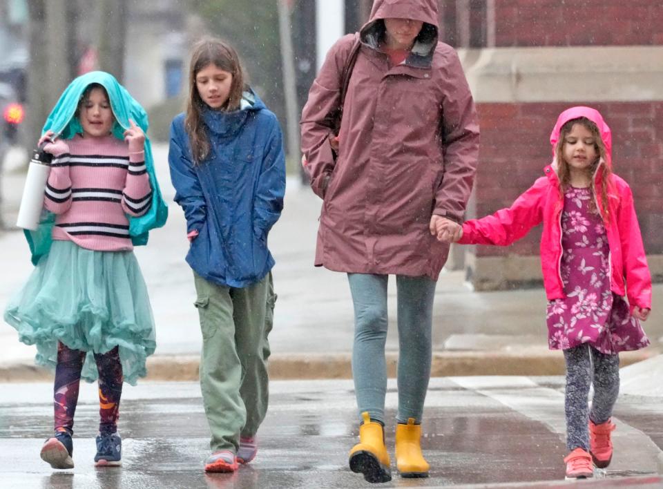 Eight-year-old Cora (left), of Madison, uses her jacket to cover her head from the rain while waiting for the light to change on East Saint Paul Avenue and North Broadway in Milwaukee with her grandmother, Caren Klarman, on Friday, March 8, 2024. Cora, who was with her sisters Willow, 10, and Maisie 6, along with her mother, Christina Miller (all not pictured), had a day off school and were headed to a hair appointment.

with her ,