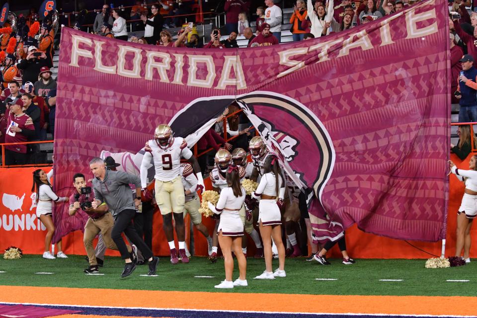 Nov 12, 2022; Syracuse, New York, USA; Florida State Seminoles head coach Mike Norvell (left) and defensive end Derrick McLendon II (9) lead their team onto the field before a game against the Syracuse Orange at JMA Wireless Dome. Mandatory Credit: Mark Konezny-USA TODAY Sports ORG XMIT: IMAGN-491377 ORIG FILE ID: 20221112_tbs_bk3_167.JPG