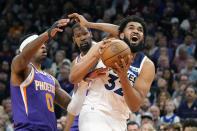 Minnesota Timberwolves center Karl-Anthony Towns, right, drives past Phoenix Suns forward Torrey Craig (0) and Suns forward Kevin Durant during the first half of an NBA basketball game Wednesday, March 29, 2023, in Phoenix. (AP Photo/Ross D. Franklin)