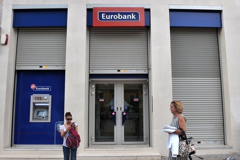 Women walk past a Eurobank branch in Athens on October 5, 2012. Eurobank on Thursday reported a net loss of 1.095 billion euros ($1.44 billion) over the first nine months of 2012, after writing off six billion euros to help the country reduce its sovereign debt