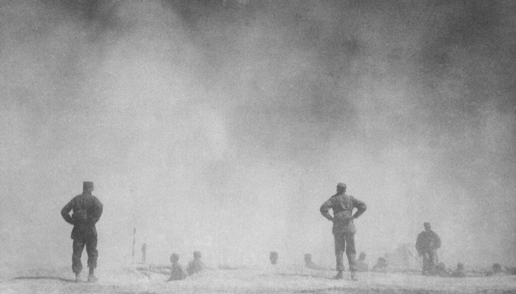 American Gen. HP Storke and other military personnel emerge from their foxholes to observe the atomic bomb explosion