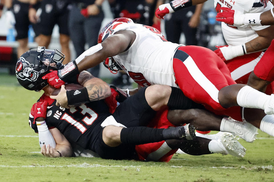 North Carolina State's Devin Leary (13) is sacked by Texas Tech's Tyree Wilson, bottom, and Bryce Ramirez during the first half of an NCAA college football game in Raleigh, N.C., Saturday, Sept. 17, 2022. (AP Photo/Karl B DeBlaker)