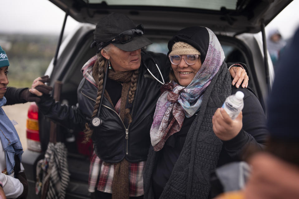 Julia Paredes, right, of Peru, gets a hug from volunteer Karen Parker, after crossing the border with Mexico nearby, Thursday, April 25, 2024, in Boulevard, Calif. Mexico has begun requiring visas for Peruvians in response to a major influx of migrants from the South American country. The move follows identical ones for Venezuelans, Ecuadorians and Brazilians, effectively eliminating the option of flying to a Mexican city near the U.S. border. (AP Photo/Gregory Bull)