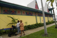 Krystina Francois, right, and Francesca Menes, children of Haitian immigrants to the U.S. and co-founders of the Black Collective, walk past the Mache Ayisyen, or Haitian Market, Tuesday, Sept. 21, 2021, in Miami. Menes and Francois, whose advocacy organization focuses on the political needs and economic empowerment of Black people across the African diaspora, have called for the Biden administration to immediately suspend plans to remove migrants via planes bound for Haiti. (AP Photo/Rebecca Blackwell)