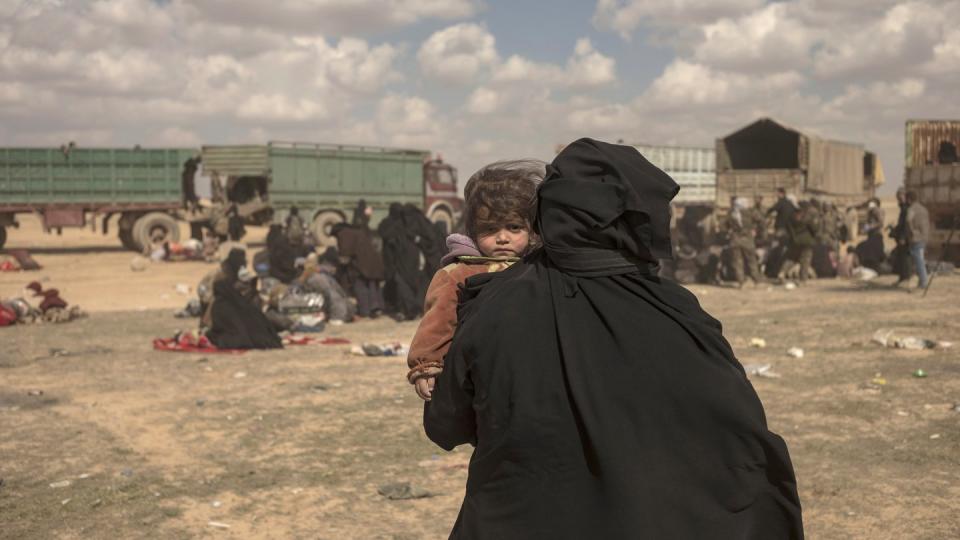 Eine Frau trägt ihr Kind durch ein Lager im syrischen Baghus, in dem Angehörige von IS-Kämpfern untergebracht sind. Foto: Gabriel Chaim/AP/Archiv