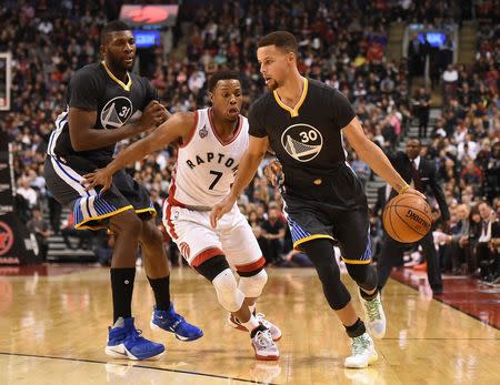 Dec 5, 2015; Toronto, Ontario, CAN; Golden State Warriors guard Stephen Curry (30) dribbles past Toronto Raptors guard Kyle Lowry (7) and Warriors center Festus Ezeli (31) in the second quarter at Air Canada Centre. Mandatory Credit: Dan Hamilton-USA TODAY Sports