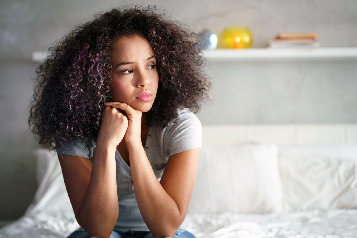 young woman looking anxious sitting on the bed