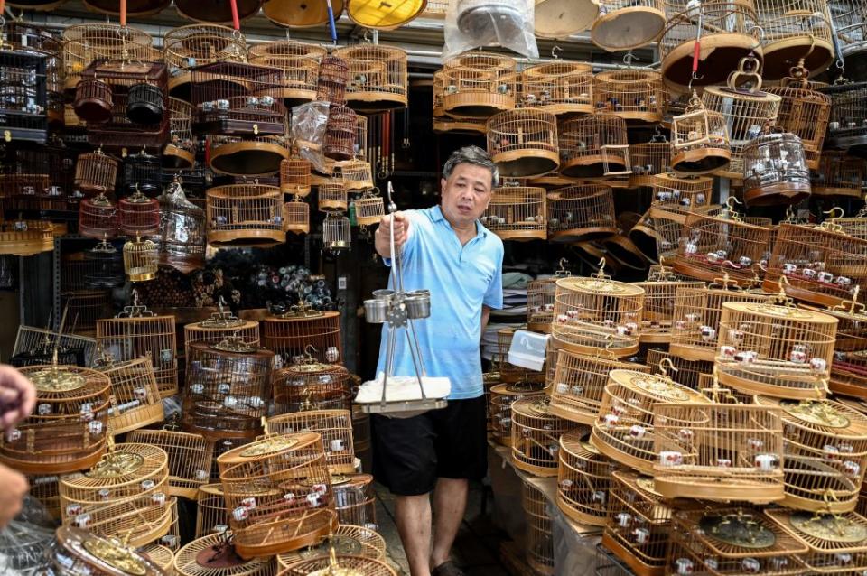 A bird cage vendor shows a bird rack to a customer at a pet market in Beijing on July 7, 2021. Source: Getty