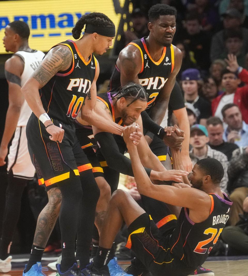 Phoenix Suns players Damion Lee (10), Ish Wainright (12) and Deandre Ayton (22) help up teammate Mikal Bridges (25) after being fouled by the Brooklyn Nets at Footprint Center on Jan. 19, 2023.