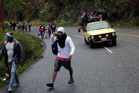 Migrants from Honduras, part of a new caravan from Central America trying to reach the United States, walk along a road as others ride in a truck as they hitch a ride, in Esquipulas, Guatemala January 16, 2019. REUTERS/Jorge Cabrera