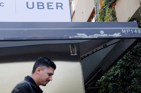 A man walks by under an Uber logo in Mexico City, Mexico February 6, 2018. Picture taken on February 6, 2018. REUTERS/Carlos Jasso