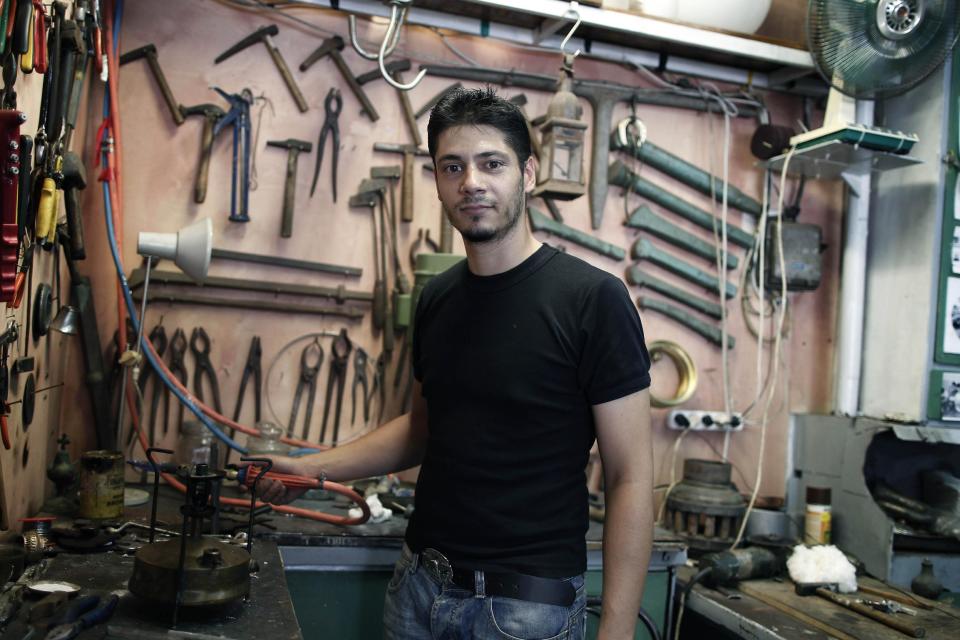 WITH STORY GREECE VOICES BY NIKOS PAPHITIS : Metalworking craftsman Apostolos Liamiras, 26, poses in his traditional coppersmith’s shop in the Psyrri district of central Athens, on Thursday, Aug. 23, 2012. As Greek Prime Minister Antonis Samaras sets off around Europe to plead for more time to achieve the country’s tough reform targets, austerity-weary Greeks are bracing for new pain but mostly expect to stay in the 17-nation eurozone, come what may. Liamiras said it would have been better if Greece had never joined the currency union. “Leaving it wouldn’t do any good, it would make things worse and create bigger problems,” he said.(AP Photo/Petros Giannakouris)