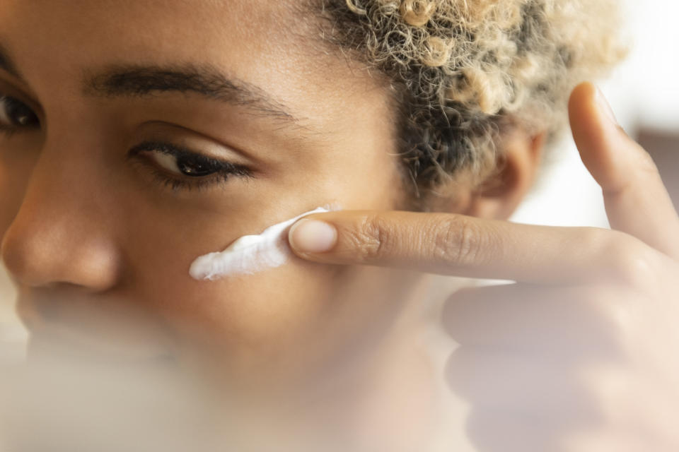 Young woman applying moisturizer (Photo: Jamie Grill via Getty Images)