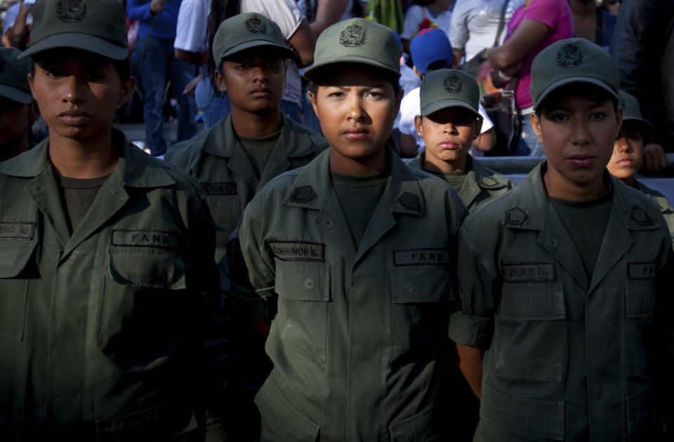 Women soldiers wait for the the arrival of Venezuela's President Nicolas Maduro in Bolivar Square for a rally to commemorate International Women's Day in Caracas, Venezuela, Saturday, March 8, 2014. (AP Photo/Alejandro Cegarra)