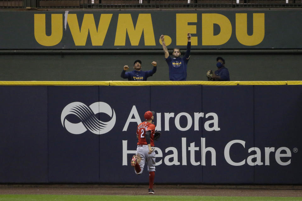 Members of the Milwaukee Brewers bullpen celebrate as Cincinnati Reds' Nicholas Castellanos (2) watches a two-run home run hit by Brewers' Justin Smoak during the third inning of a baseball game Monday, Aug. 24, 2020, in Milwaukee. (AP Photo/Aaron Gash)