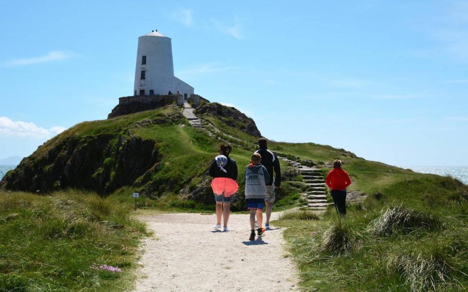 Holiday makers visit Llanddwyn Island Lighthouse (Twr Mawr) of the coast of Anglesey - Tim Snow