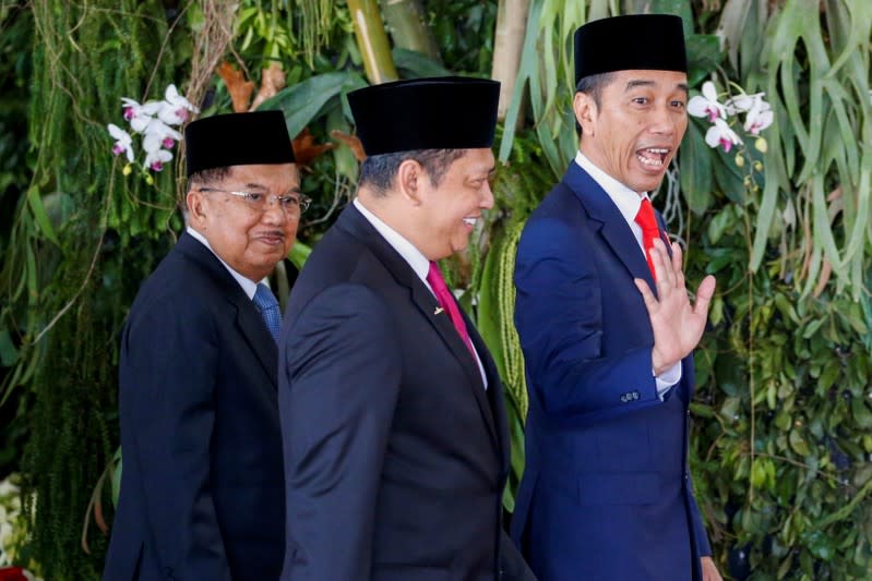 Indonesian President Joko Widodo reacts to journalists as Vice President Jusuf Kalla looks on, before the president's inauguration for the second term, at the House of Representatives building in Jakarta