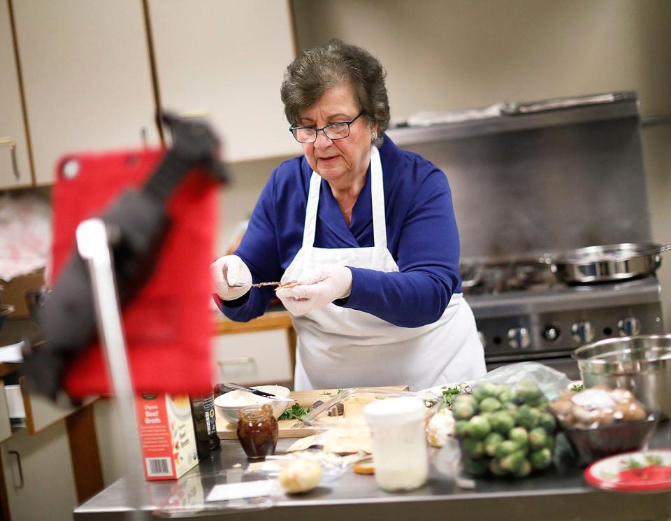 Joyce Bethoney, of Hingham, makes Christmas dinner in the Hingham senior center's kitchen while filmed by two iPads Thursday, Dec. 16, 2021.