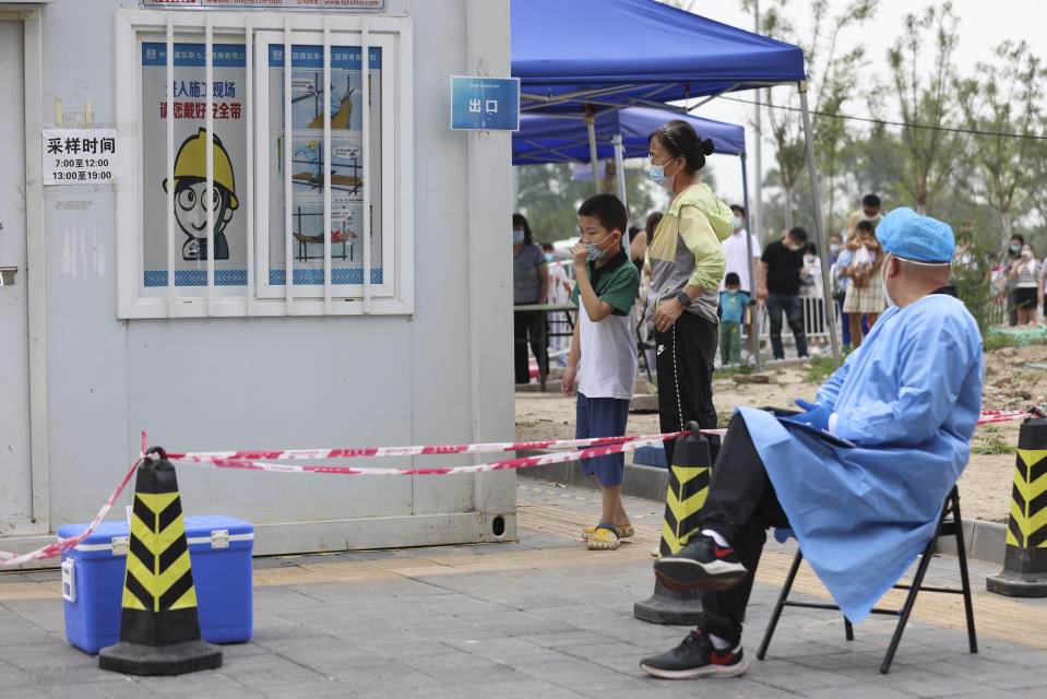 BEIJING, CHINA - JUNE 30:  A security guard in protective clothing sit in front of residents at a COVID-19 test site on June 30, 2022 in Beijing, China. China is trying to contain a spike in coronavirus cases in the capital Beijing, Local authorities have initiated mass testing in most districts, placing some neighborhoods under lockdown where cases are found in an effort to prevent the spread of COVID-19.  (Photo by Lintao Zhang/Getty Images)