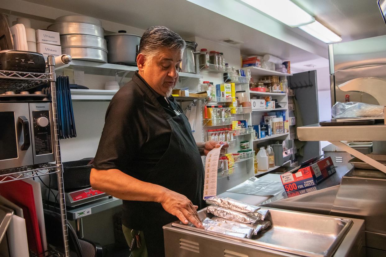 Frank Jimenez juggles answering telephone calls, preparing food and serving customers at Babalu's Cuban Cafe, Friday, July 7, 2023, in Old Town Fort Collins, Colo. Frank and his wife, Rosa, are trying to keep their cafe open as they contend with Rosa's stage 4 colon cancer diagnosis and treatments.