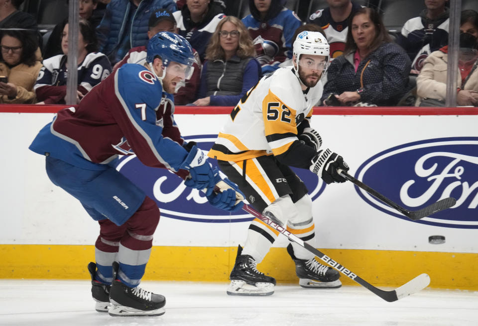 Pittsburgh Penguins defenseman Mark Friedman, back, passes the puck past Colorado Avalanche defenseman Devon Toews in the second period of an NHL hockey game Wednesday, March 22, 2023, in Denver. (AP Photo/David Zalubowski)