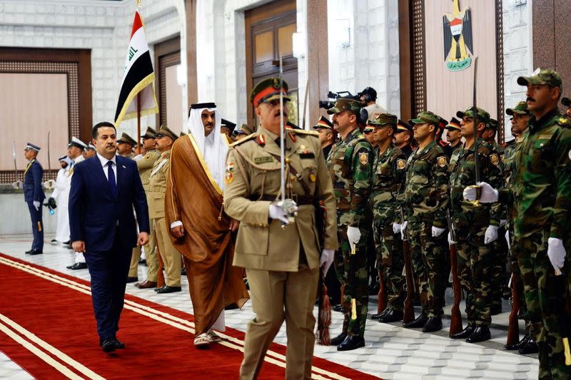 Iraqi PM Mohammed Shia al-Sudani walks with Qatar's Emir Sheikh Tamim bin Hamad al-Thani during a welcome ceremony, in Baghdad