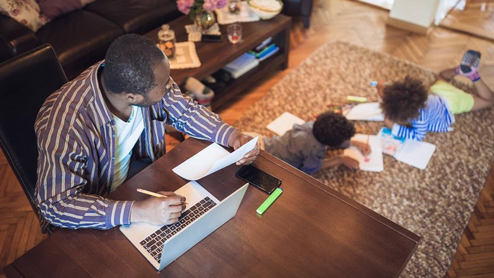 Father working from home while his two children are playing in the living room.