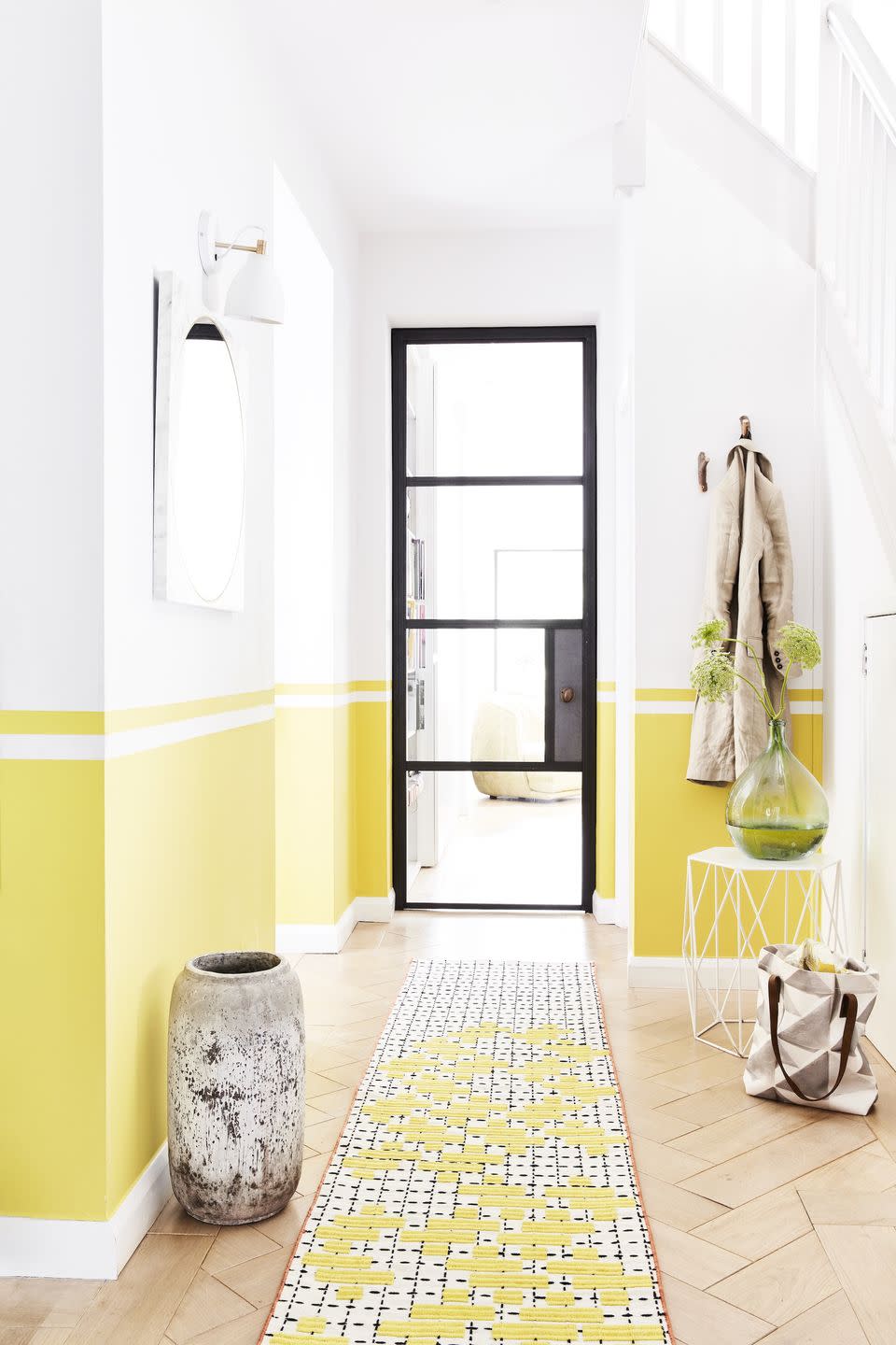 hallway with a black framed door, walls are painted yellow half way up from the bottom line