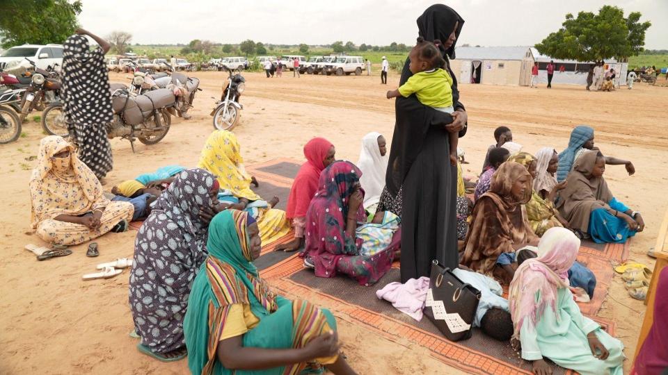 Women sitting on mats on the ground at a camp in Adré 