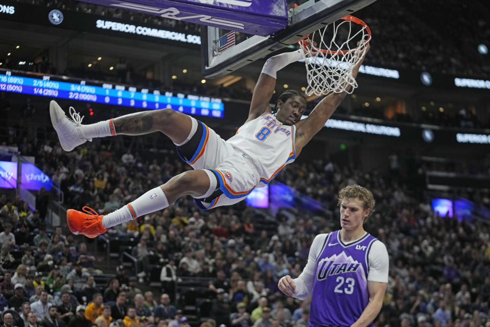 Oklahoma City Thunder forward Jalen Williams (8) holds on to the rim after dunking against Utah Jazz forward Lauri Markkanen (23) during the first half of an NBA basketball game Thursday, Jan. 18, 2024, in Salt Lake City. (AP Photo/Rick Bowmer)