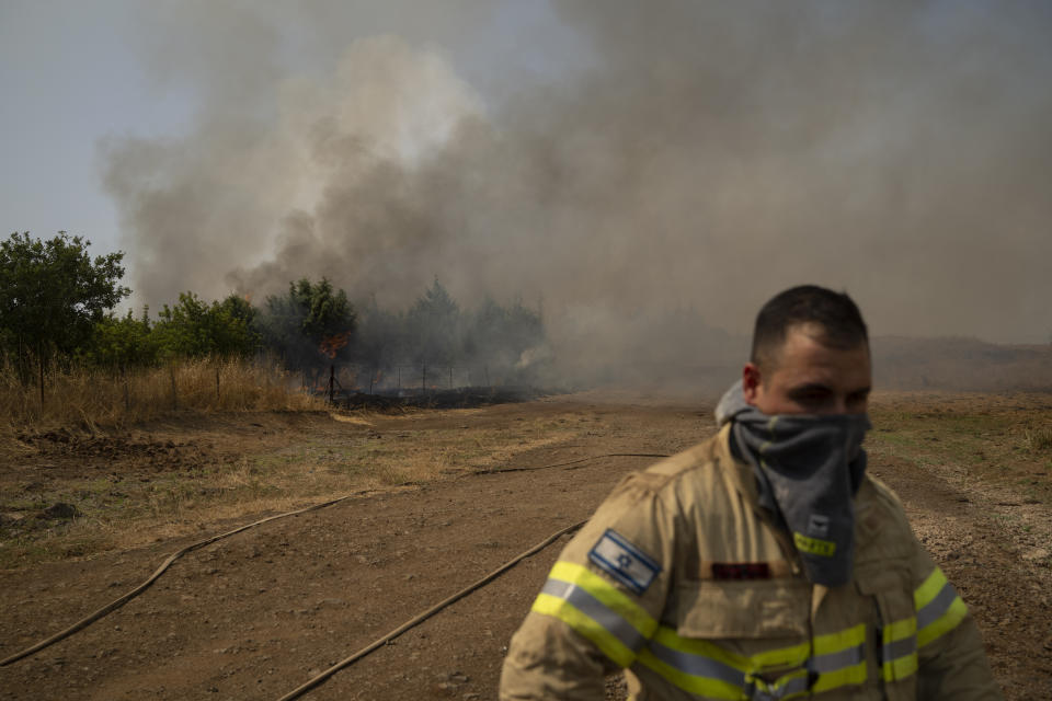 A firefighter walks near fire burning an area after a Lebanese shelling, in the Israeli-controlled Golan Heights, Thursday, June 13, 2024. (AP Photo/Leo Correa)